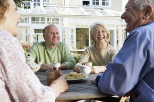 Two senior couples having tea outdoors (focus on couple in background)