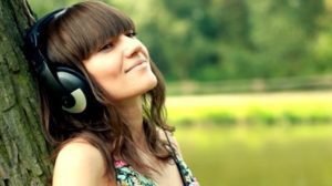 stock-footage-woman-with-headphones-listen-to-the-music-in-the-park