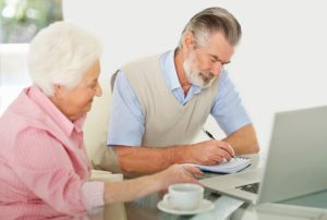 Portrait of a relaxed mature couple with a notepad and laptop working on finances